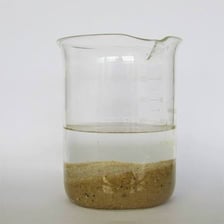 A glass of cloudy water containing visible suspended sediment.