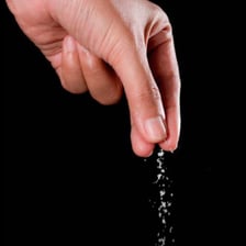 A small pinch of salt held between fingers, illustrating a tiny amount.