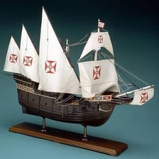 A reconstructed Portuguese caravel with sails on the water.