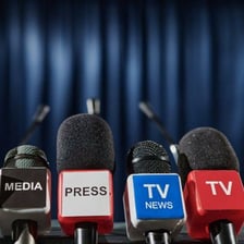 A newspaper beside a television broadcasting a news program