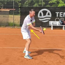 A tennis player striking a ball in midair before it reaches the court.