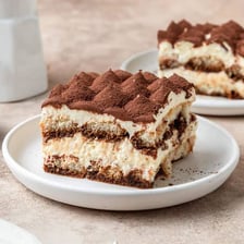 A slice of tiramisu alongside a small cup of espresso.