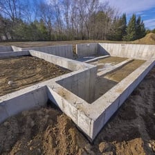 A concrete foundation supporting the walls of a house under construction.