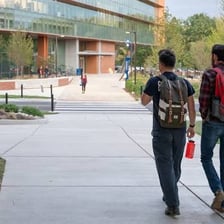 A university student walking across a college campus.