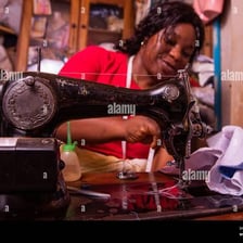 A seamstress sews fabric into a dress.