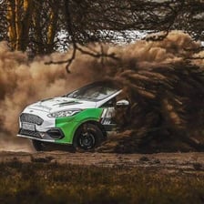 A rally car swinging around a corner during a handbrake turn.
