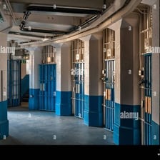 A prison corridor with barred cell doors.