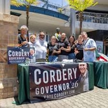Several election candidates speaking with people at a campaign event.