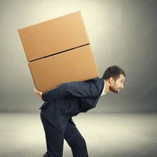 A person carrying a heavy box with effort.