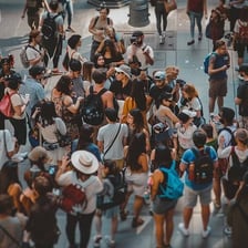 A crowded public scene with people moving about noisily