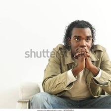 A visibly worried person sitting with clasped hands.