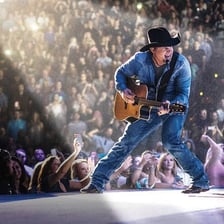 Garth Brooks performing on stage with a microphone.