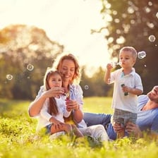 Children blowing and playing with floating soap bubbles.