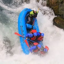 People traveling through rapids in an inflatable raft