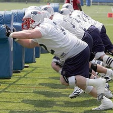 American football offensive linemen blocking during a play