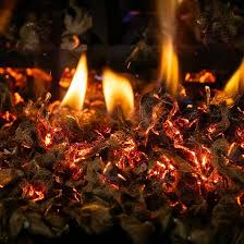 Small glowing cinders remaining in a fireplace after a fire.