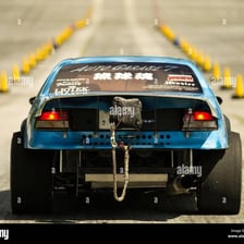 A funny car drag racer deploying a parachute to slow down.
