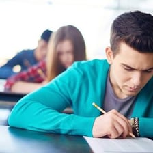 A student completing a second examination in a classroom.