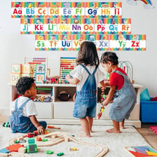 A young child practices alphabet letters in a classroom.