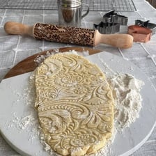 A rolling pin dusted with flour beside prepared dough.