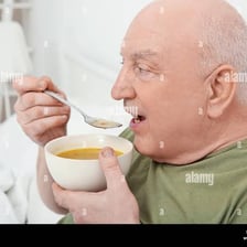 A person drinking soup noisily from a spoon