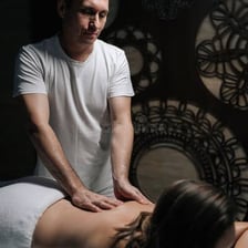 A professional masseur kneading a client's back.