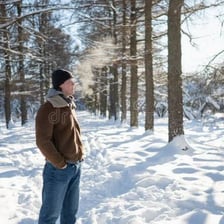 A person breathing out, with the exhaled air visible in cool conditions.