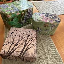 A decorated craft object featuring cut-out paper pieces in a decoupage design