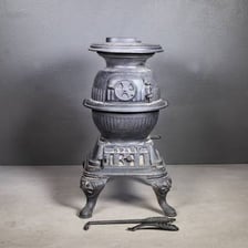 An antique cast-iron stove with a rounded, bulging body.