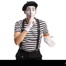 A mime performer signaling silence with a finger over their lips