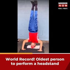 A person balancing upside down on their head with their legs raised.