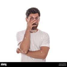 An embarrassed person covering their face in a public setting.