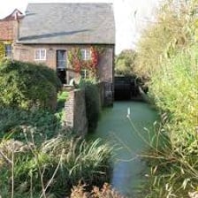 A water channel carrying a stream beside a historic mill.