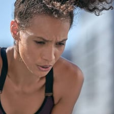 A tired runner leaning forward and catching their breath after exercise.