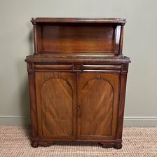 An antique chiffonier serving as a low sideboard cupboard.