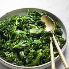 A bowl containing fresh kale and spinach leaves