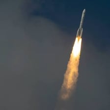 A rocket rising from the launchpad with its booster engines firing.