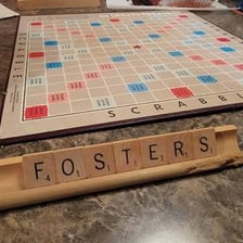 A Scrabble rack showing seven tiles being played on the board