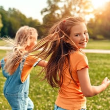 Children running and playing together in a grassy meadow.