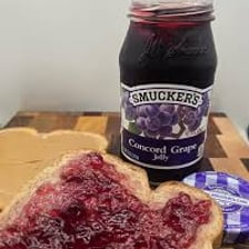 A jar of American grape jelly with jelly spread on toast