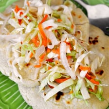 A traditional Salvadoran pupusa served with curtido and tomato sauce.
