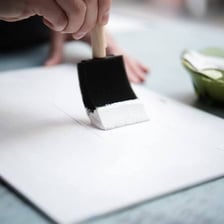 An artist applying primer to a canvas before painting.