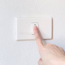 A finger presses a small mechanical button.