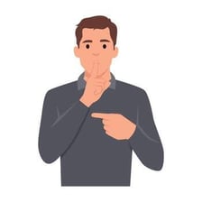 A person holding a finger to their lips to request silence.