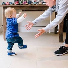 A toddler taking unsteady steps while learning to walk.
