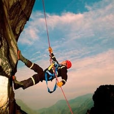 A climber descending a cliff by abseiling on a rope