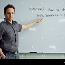 A teacher giving homework instructions to students in a classroom.