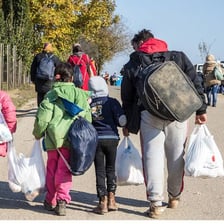 A displaced family carrying luggage while leaving an affected area.