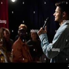 A comedian performing while an audience laughs.