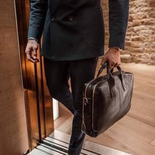 A lawyer carrying a black leather briefcase near a courthouse